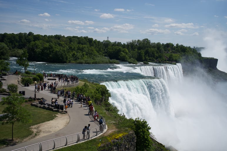 Crowds along a railing overlooking a wide, misty waterfall