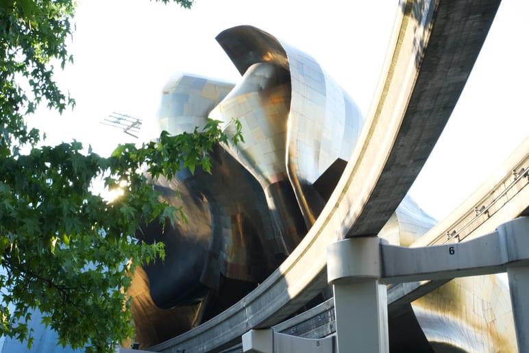 Sunlight catching the curved, reflective metal panels of a sculptural building