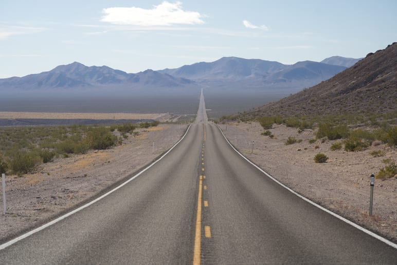 A straight desert highway stretching toward distant mountains