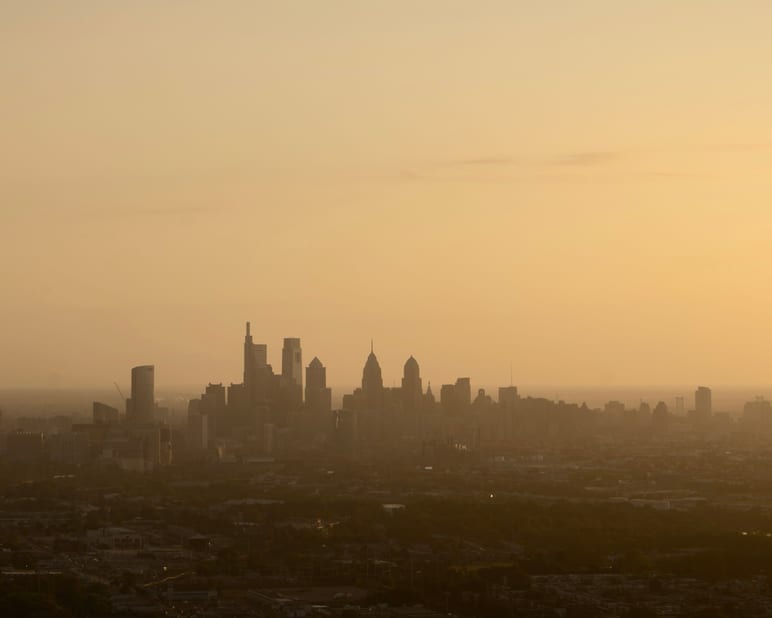 A city skyline silhouetted against a hazy, golden sunset