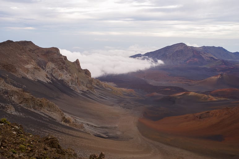 View across a volcanic crater with clouds filling the valley below