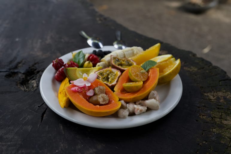 A plate of sliced tropical fruit on a weathered wood surface