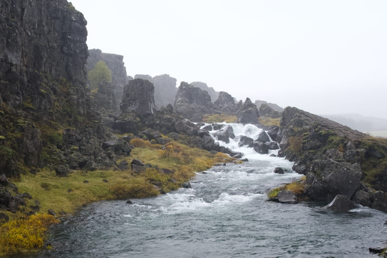 A river cuts through a jagged rock gorge with cascading rapids