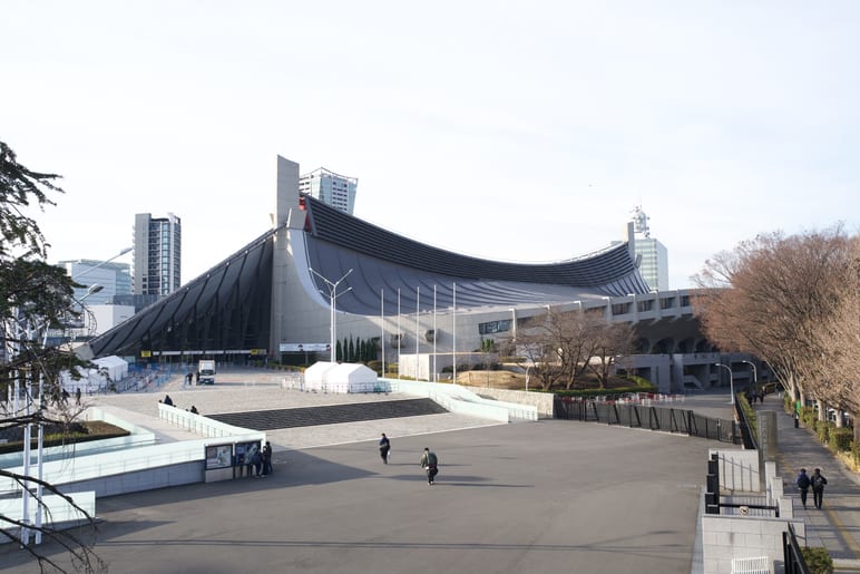 A large curved roof sweeps over a plaza with a few pedestrians