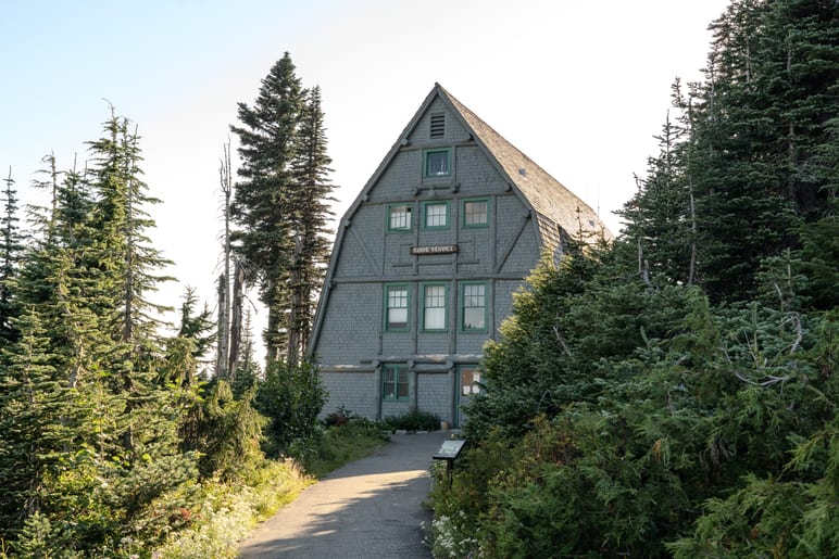 Stone and timber lodge with a steep gabled roof among evergreen trees